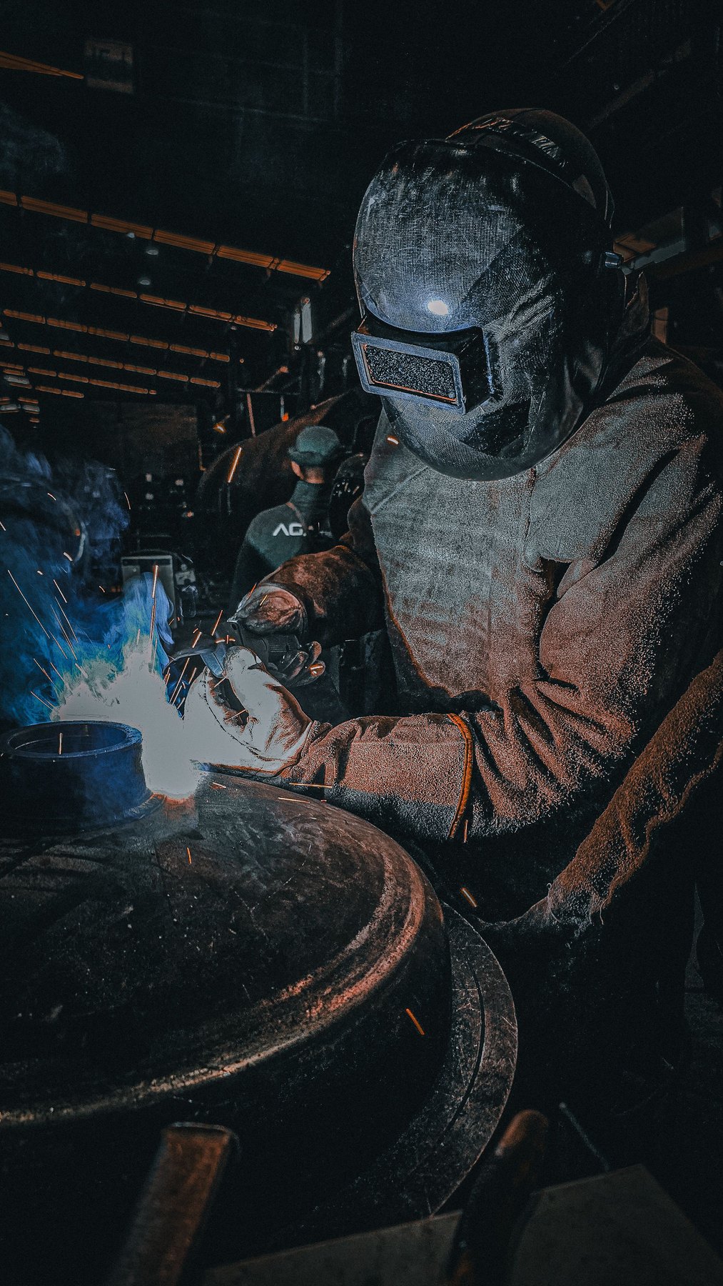 Steel fabrication by a welder wearing a protective welding helmet and gloves